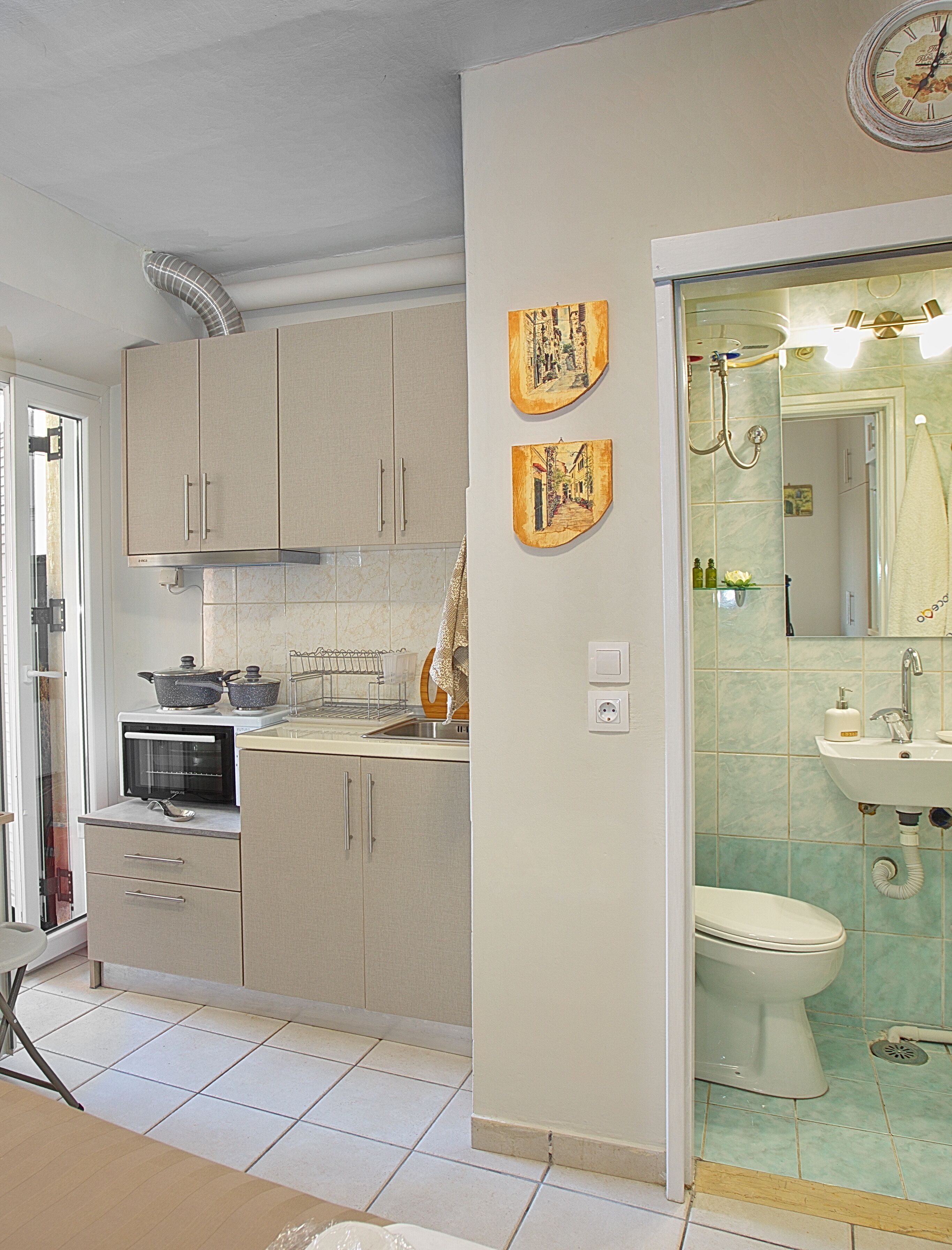 Et moderne køkken med indbyggede apparater, et spiseområde med bord og stole, og et badeværelse med vask og toilet.