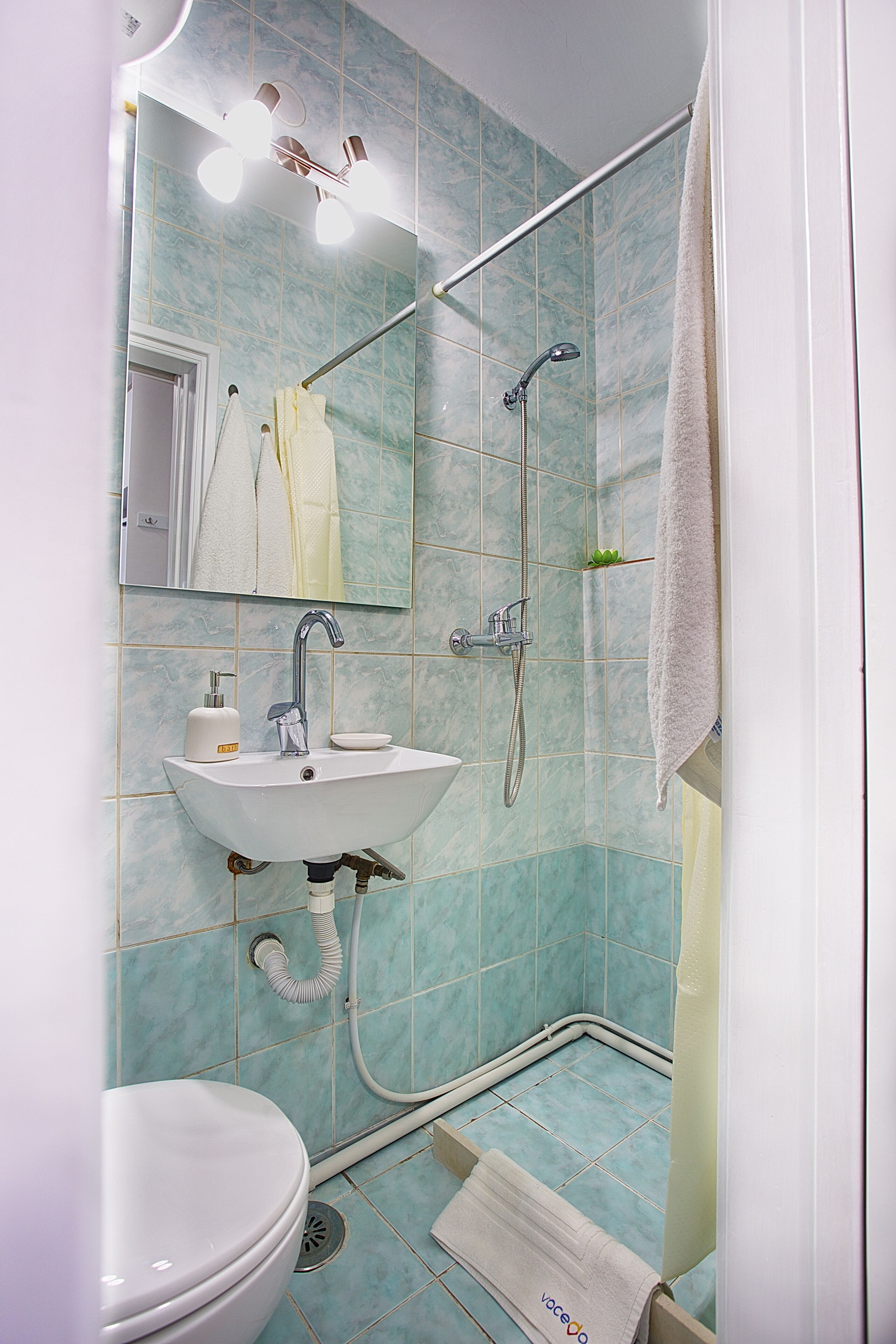 Un baño con lavamanos, espejo y ducha blancos.