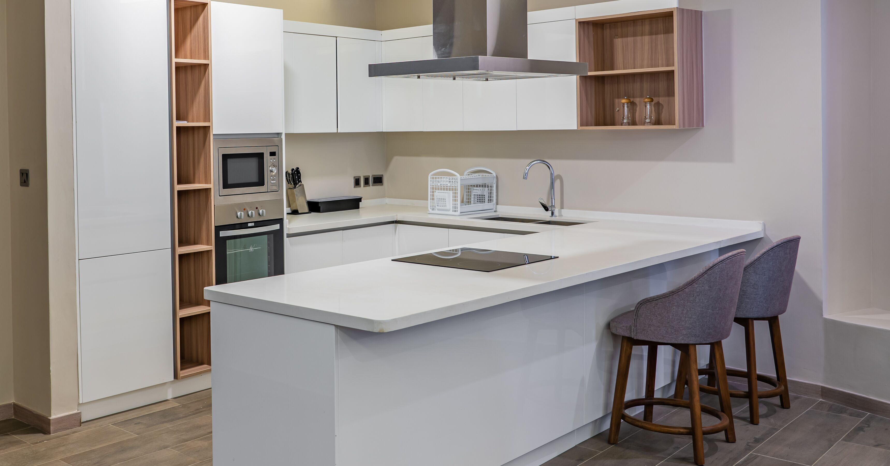 A modern kitchen with a central island, built-in oven, microwave, and a stainless steel range hood.