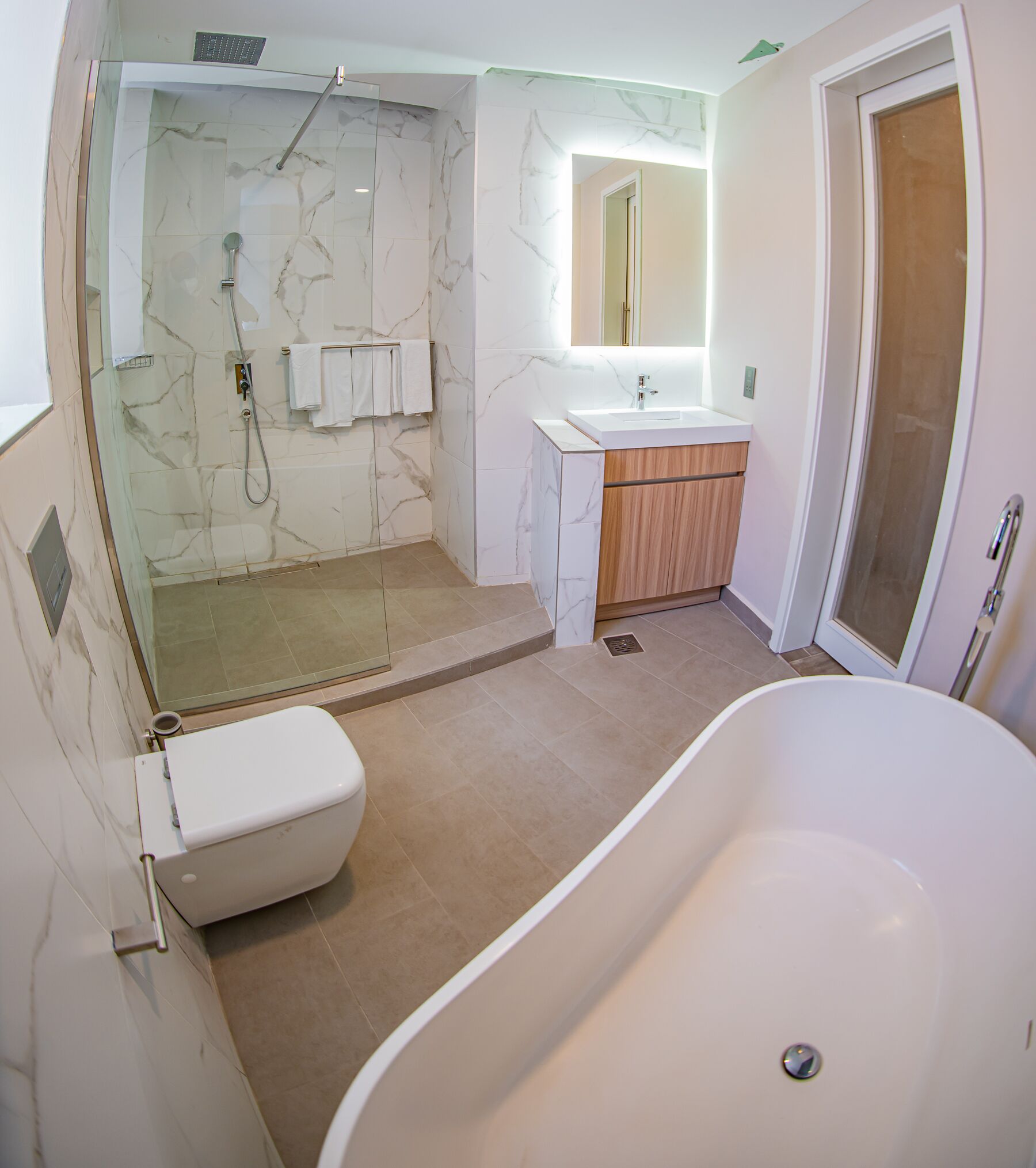 A modern bathroom with a glass-enclosed shower, a freestanding bathtub, and a vanity with a mirror.