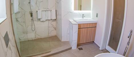 A modern bathroom with a glass-enclosed shower, a freestanding bathtub, and a vanity with a mirror.