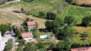 An aerial view of a residential area with houses, a swimming pool, and surrounding greenery.