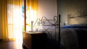 A bedroom with a metal bed frame, a bedside table, and a window with curtains.