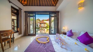 A bedroom with a bed, a bench, a view of an outdoor pool, and a door leading outside.