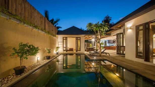 A modern house with a swimming pool, outdoor seating, and a well-lit patio area.