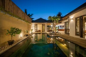 Uma casa moderna com piscina, área de estar externa e um pátio bem iluminado.