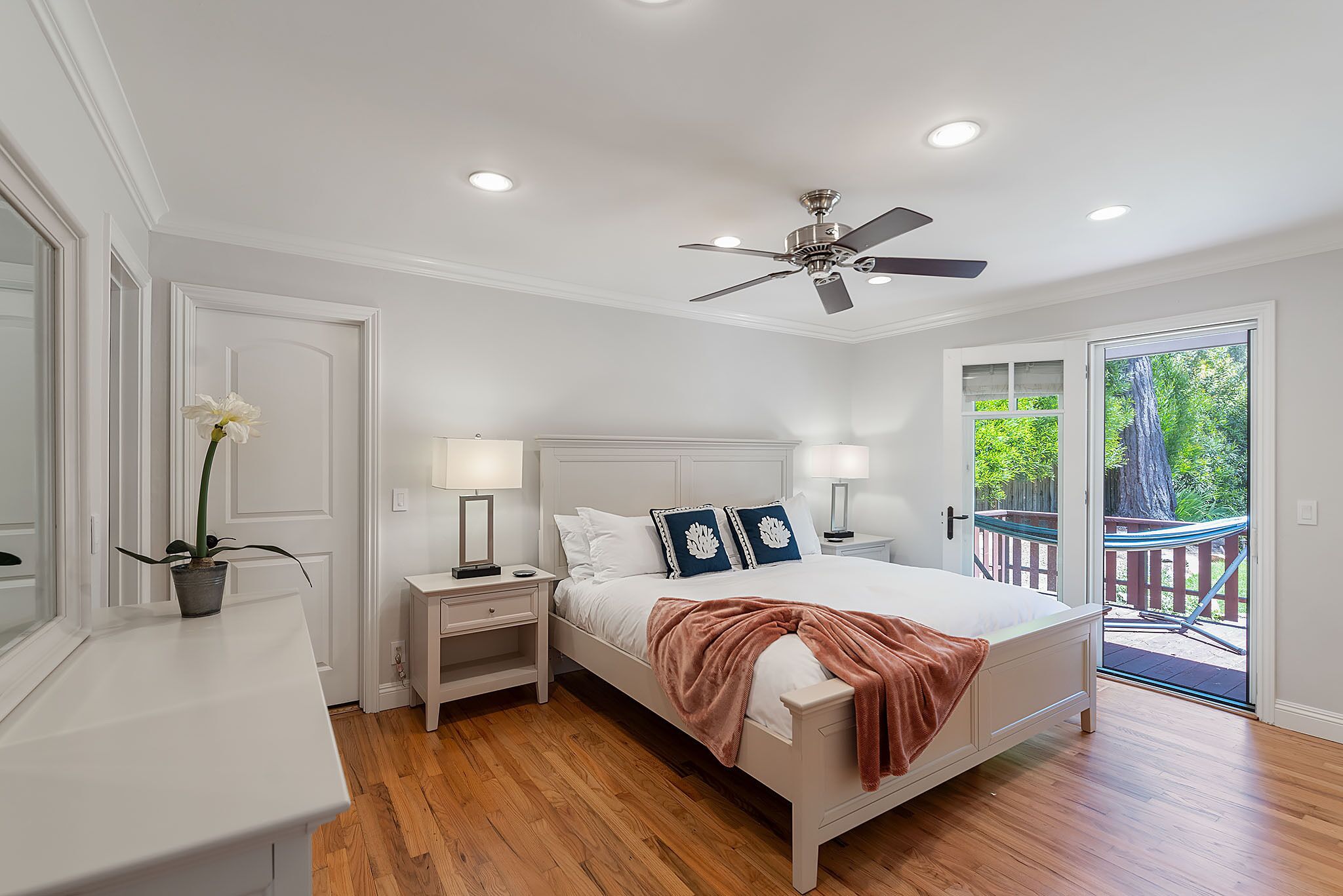 Un dormitorio con cama, mesitas de noche, ventilador de techo y vistas al exterior.