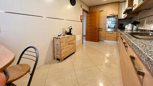 Eine moderne Küche mit Holzschrank, einem kleinen Tisch und einem Stuhl.