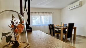 Ein Essbereich mit Holztisch, Stühlen und einer Glaskuppel mit getrockneten Blumen.