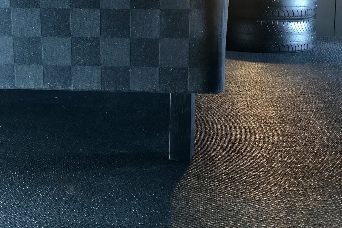A checkered sofa with a textured cushion, a tire, and a textured floor.
