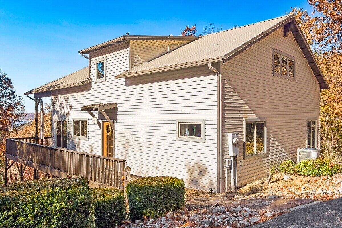 A two-story white building with a sloped roof, a wooden deck, and a small porch.