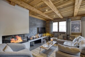A cozy living room with a fireplace, comfortable seating, and a stone wall.