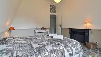 A bedroom with a bed, bedside table, lamp, and a fireplace.