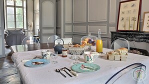A dining table set with breakfast items, including bread, fruit, and a teapot. - Domaine des Longrais (Saint-Thurial)