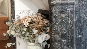 Un jarrón blanco con un arreglo floral sobre una superficie de mármol.