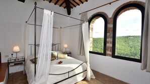 A four-poster bed with a canopy, two bedside tables with lamps, a view through arched windows, and a brick wall. - Case Domine, Radda in Chianti, Siena and Chianti (Radda in Chianti)