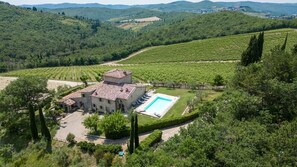 Une villa avec piscine, entourée d’une végétation luxuriante et de vignobles.