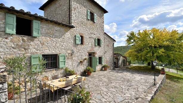 A stone building with a courtyard, a table with chairs, and potted plants. - Case Domine, Radda in Chianti, Siena and Chianti (Radda in Chianti)