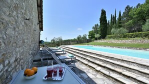 A poolside area with stone steps leading to a pool, a table with a tray of drinks, and a stone wall. - Case Domine, Radda in Chianti, Siena and Chianti (Radda in Chianti)