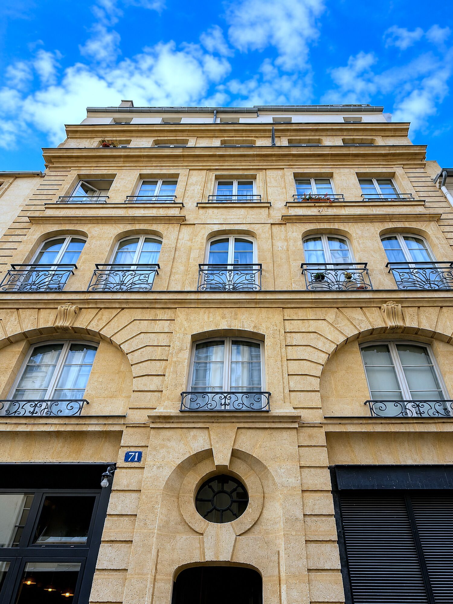 A multi-story building with a classical architectural style, featuring arched windows and decorative metal railings on the balconies.