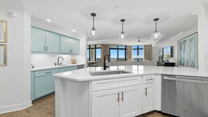 Une cuisine moderne avec des meubles blancs, un grand îlot central et des luminaires suspendus.
