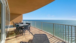A balcony with a table and chairs, a view of the ocean, and a railing.