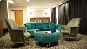 Un salon moderne avec un canapé de couleur turquoise, deux fauteuils et une table basse ronde.