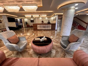 A hotel lobby with marble flooring, a reception desk, and two armchairs with cushions. - El Emin İstanbul Hotel (Istanbul)