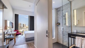 A modern hotel room with a bed, desk, chair, and a large window offering a city view. - INK Hotel (Dubai)