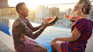 A man and a woman sitting by a pool with a cityscape in the background. - INK Hotel (Dubai)