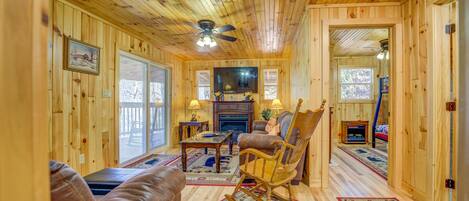 A wooden interior with a fireplace, leather sofa, and a rocking chair.