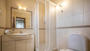 Een badkamer met een wastafel, spiegel, douchecabine en toilet.
