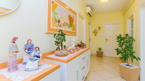 Un passadís amb una taquilla de recepció decorada amb figures ornamentals, una obra d'art emmarcada i plantes en testos.