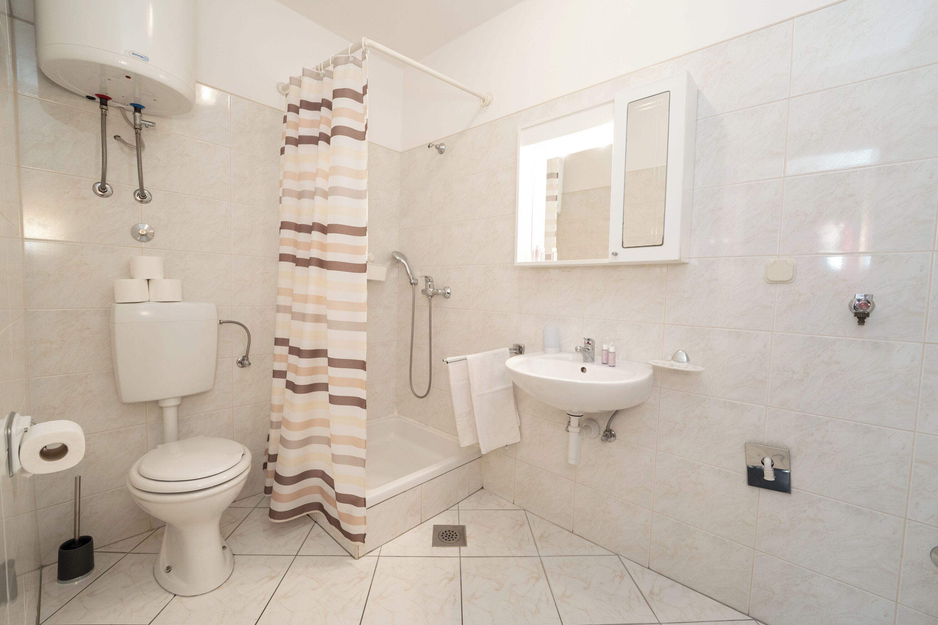 A modern bathroom with a toilet, shower, sink, and a mirror.