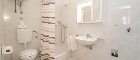 A modern bathroom with a toilet, shower, sink, and a mirror.