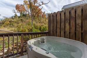 Jacuzzi con cerca de madera y vista a un paisaje natural.