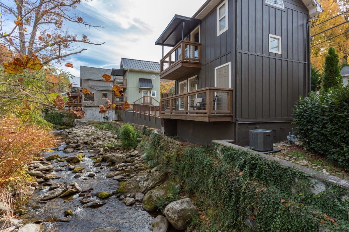 Un immeuble résidentiel doté d’un balcon, d’un chemin pavé de pierres et d’un petit ruisseau.