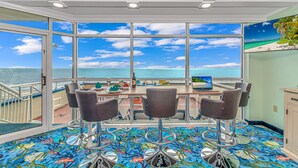 A dining area with a large window overlooking the ocean, a table set for four, and a colorful carpet. - 🐠Oceanfront | Indoor Heated Water Park + Lazy River | Dunes Village Resort 701 (Myrtle Beach)