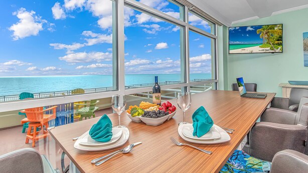 A dining area with a view of the ocean, a laptop, and a bowl of fruit on the table. - 🐠Oceanfront | Indoor Heated Water Park + Lazy River | Dunes Village Resort 701 (Myrtle Beach)
