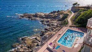 Une piscine à l’eau d’un bleu cristallin, entourée d’un paysage rocheux et offrant une vue sur la mer.