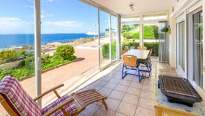 Un balcon avec vue sur la mer, une table, des chaises et un barbecue.