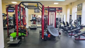 A gym with various exercise equipment, including treadmills, weight machines, and a pull-up bar area.