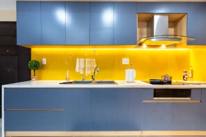 A modern kitchen with a yellow backsplash, blue cabinets, and a stainless steel range hood.