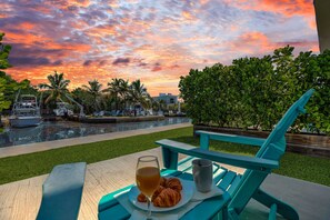 A sunset view with a pool, lounge chairs, and a table with a glass of wine and croissants. - 4. Cozy Key Largo Waterfront Studio  Dive (Key Largo)