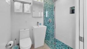 A modern bathroom with a toilet, sink, and shower.