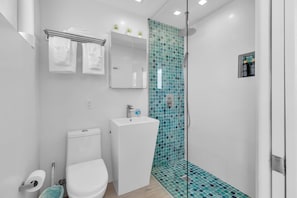 A modern bathroom with a toilet, sink, and shower.