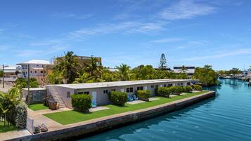 A waterfront hotel with a pool, a covered walkway, and a view of the water.