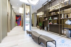 Un hall d’hôtel moderne avec un long banc, un comptoir d’accueil et un mur décoré d’une œuvre abstraite aux couleurs vives.