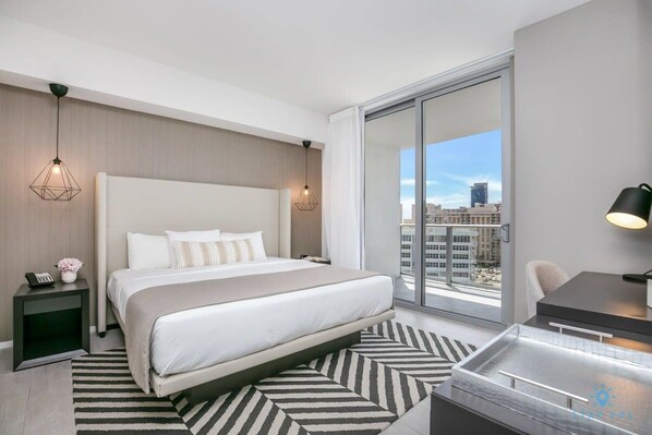 Une chambre d’hôtel moderne, dotée d’un grand lit, d’un bureau et offrant une vue sur la ville.