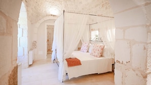 Une chambre à coucher avec un lit à baldaquin, des murs blancs et des murs en pierre.